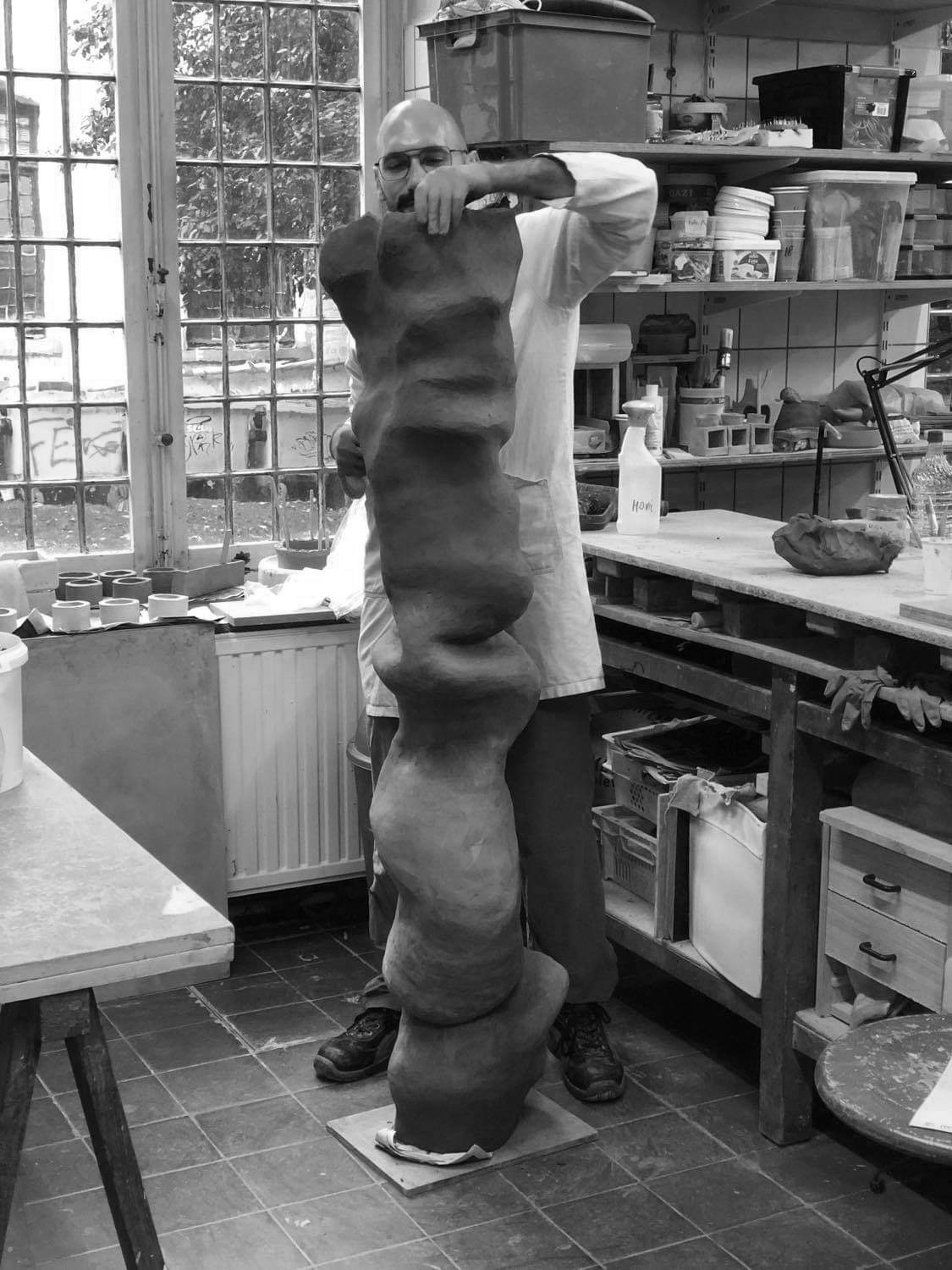 the artist in his studio modeling a large sculpture in clay